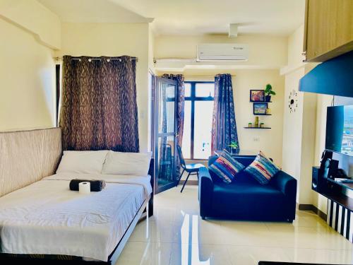 a bedroom with a bed and a couch and a chair at Mabolo Garden Flats Cebu in Cebu City