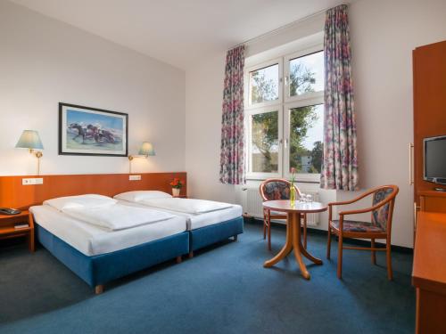 ein Hotelzimmer mit 2 Betten und einem Tisch in der Unterkunft Trip Inn Hotel Schumann in Düsseldorf