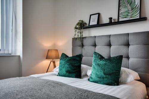 een slaapkamer met een groot bed met groene kussens bij City View Apartment in Liverpool