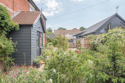 a garden with a black house and plants at Rustics, Reydon in Southwold