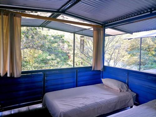 two beds in a room with two windows at Room in Cabin - Rafting Hut by The River in Lanquín