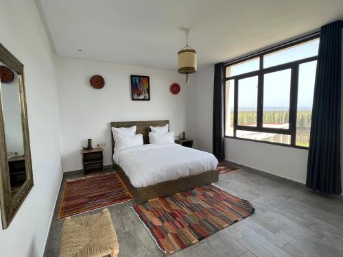 a bedroom with a bed and a large window at Dar Ayman Essaouira in Essaouira