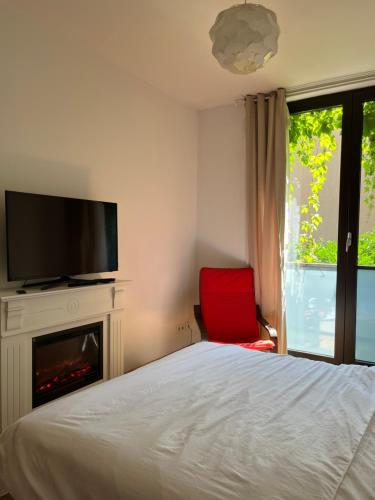a bedroom with a bed and a tv and a red chair at Apartament Lux 2 camere Nordului in Bucharest