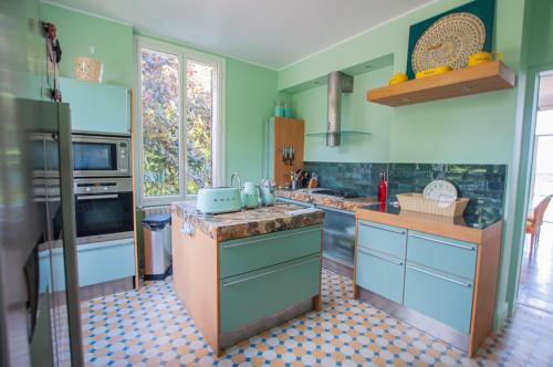 a kitchen with blue and green walls and a counter at Villa avec vue et piscine à moins d'1h de Paris in Rolleboise