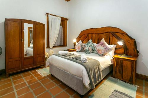 a bedroom with a large bed with a wooden headboard at Ravenscliff Manor in Oudtshoorn