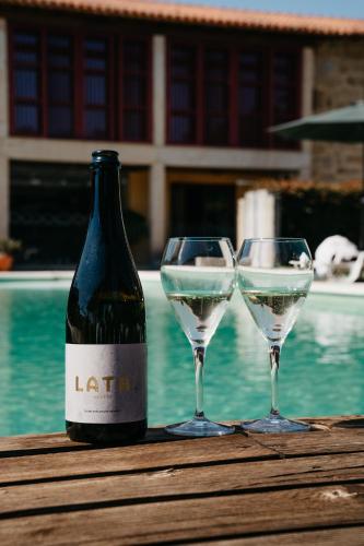 a bottle of wine and two wine glasses on a table at Casa Lata - Agroturismo e Enoturismo in Amares