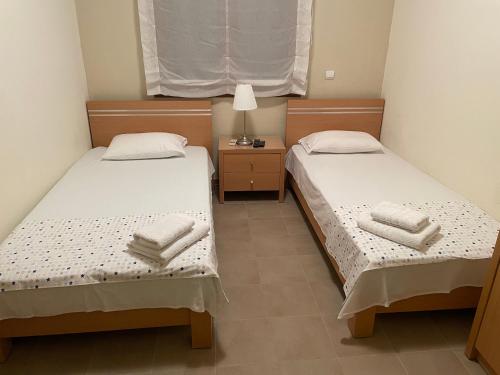 two beds in a small room with a nightstand and two towels at villa ATHINA in Kriopigi