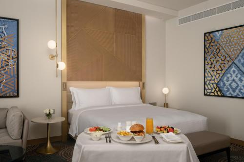 a hotel room with a bed with two tables with food on it at Slemani Rotana in As Sulaymānīyah