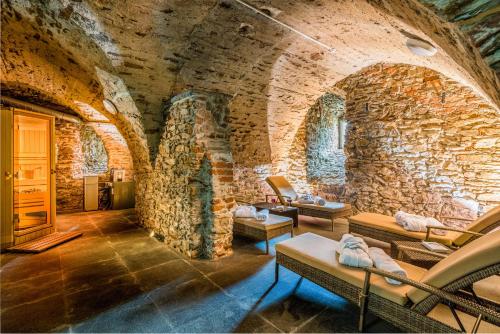 a room with a stone wall with couches and chairs at Schloss Purschenstein in Neuhausen