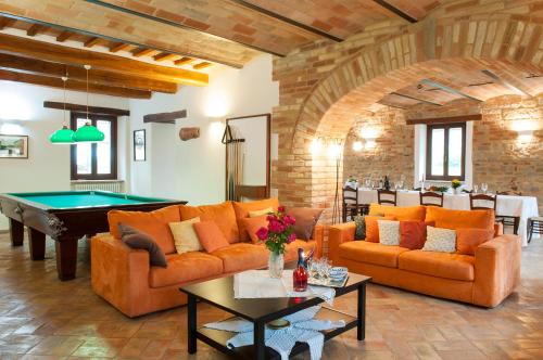 a living room with orange couches and a pool table at Collerovere Country House in SantʼAngelo in Pontano