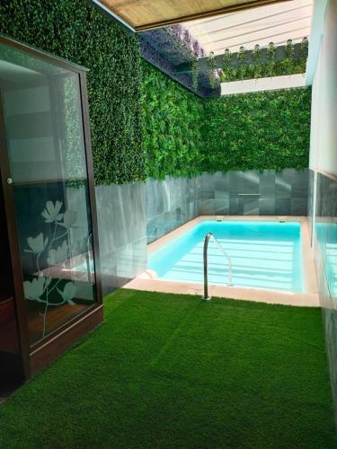 a swimming pool with a green wall at Hostal Palacio San Bartolomé in El Puerto de Santa María