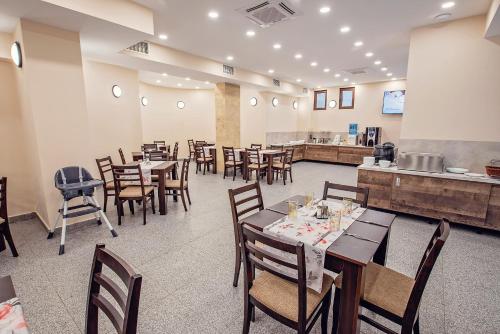a dining room with tables and chairs and a kitchen at Hotel Santa Maria in Obzor