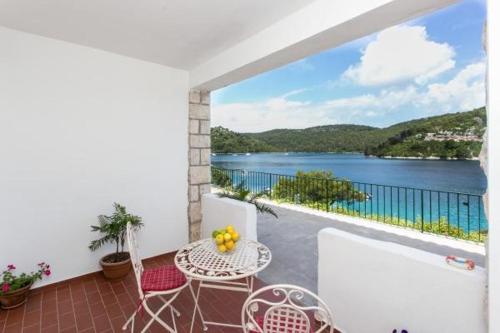 a balcony with a table and chairs and a view of the water at Guest House Busurelo in Polače