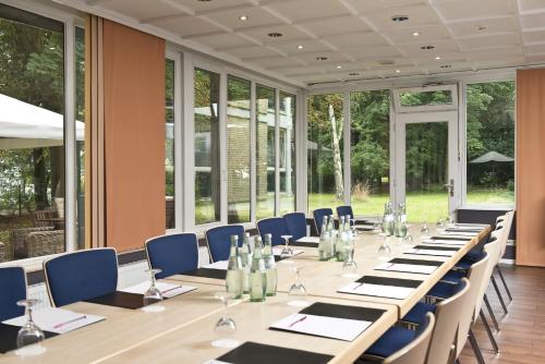 a large conference room with a long table and blue chairs at Park Hotel Hamburg Arena in Hamburg