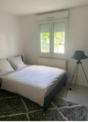 um quarto com uma cama, um candeeiro e 2 janelas em Disney land Paris - Charmant logement em Bussy-Saint-Georges