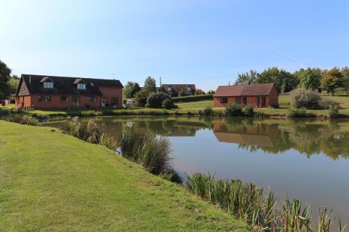 布蘭斯福德的住宿－Bransford Farm Fishery & B & B，房屋前的房屋和池塘