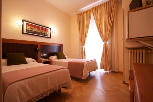 a hotel room with two beds and a flat screen tv at Hostal Greco Gran Vía Madrid in Madrid