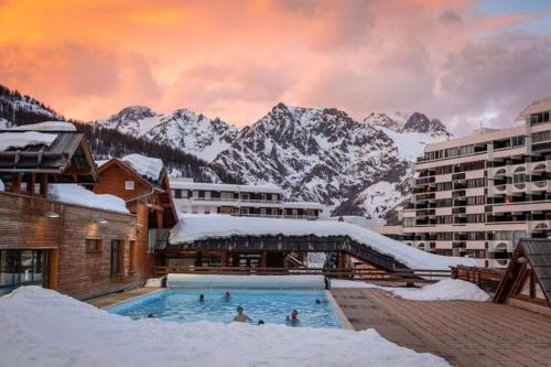 un hôtel avec une piscine entourée de montagnes enneigées dans l'établissement Appartement 4pers Rénové Pied des Pistes - Balcon Vue Montagne, à Puy-Saint-Vincent