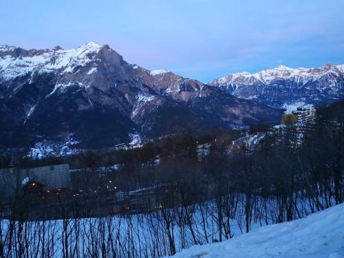 une chaîne de montagnes enneigée avec une ville au premier plan dans l'établissement Appartement 4pers Rénové Pied des Pistes - Balcon Vue Montagne, à Puy-Saint-Vincent