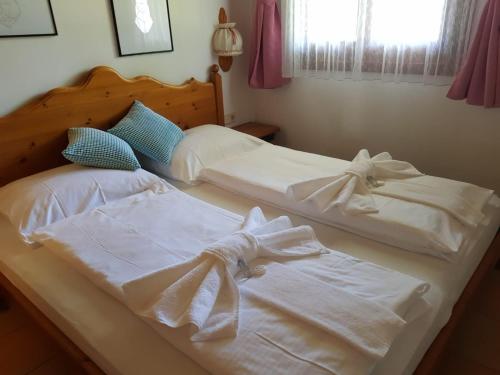 2 camas en un dormitorio con sábanas blancas y arcos en LivGood Appartements Gerlitzen, en Treffen