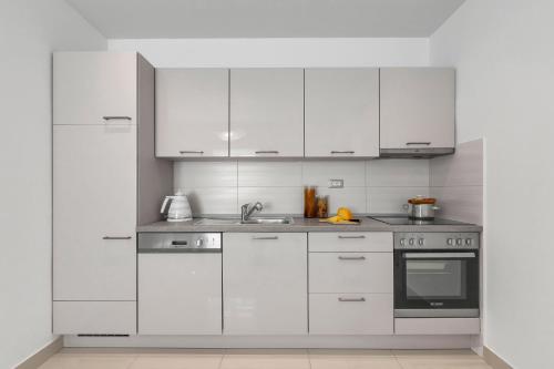 a white kitchen with white cabinets and a sink at Apartment Vranješ in Makarska