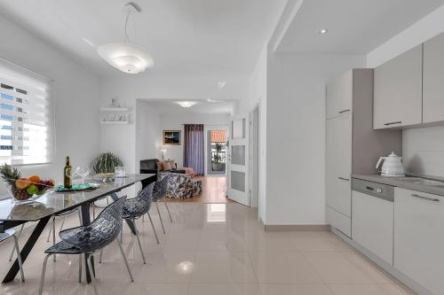 a white kitchen with a dining table and chairs at Apartment Vranješ in Makarska