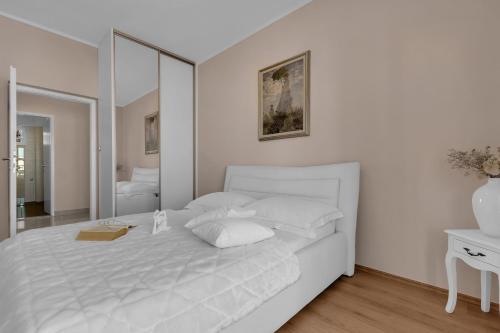 a white bedroom with a white bed and a mirror at Apartment Vranješ in Makarska