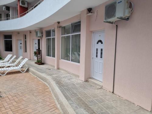 a patio with white chairs and a door on a building at Бутикови Студиа БРИТА in Kranevo