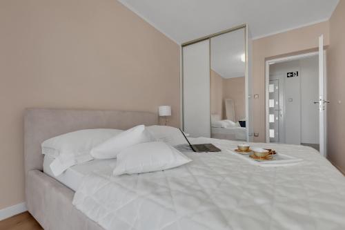 a white bedroom with a large bed with a mirror at Apartment Vranješ in Makarska