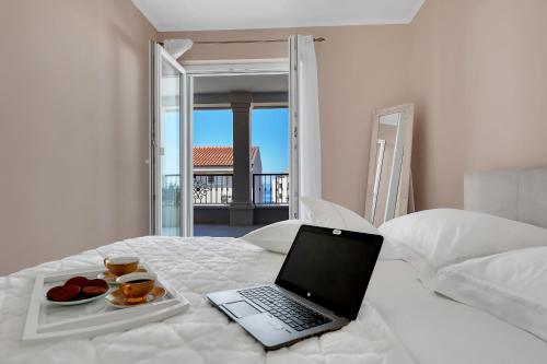 a laptop computer sitting on a bed with a plate of food at Apartment Vranješ in Makarska