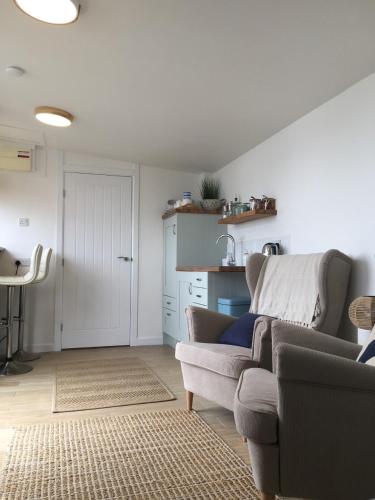 a living room with a couch and a kitchen at 1-bedroom chalet with parking on site in Looe