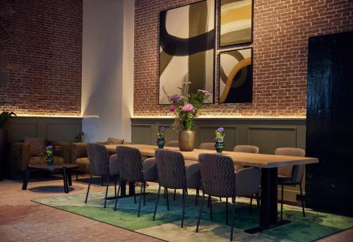 a table and chairs in a room with a brick wall at Hotel Arsenaal Delft in Delft