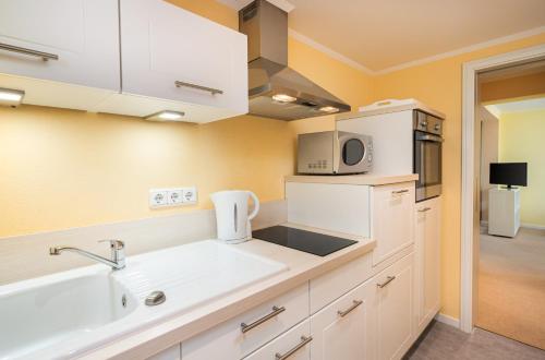 a kitchen with a sink and a microwave at Arthotel ANA Fleur in Paderborn