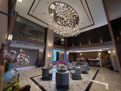 vestíbulo con lámpara de araña, mesas y sillas en CHRISTEE SUITES HOTEL en Melaka