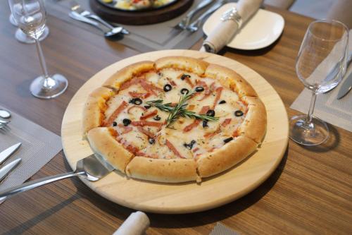 a pizza on a wooden plate on a table at VIP Hotel Doha Qatar in Doha