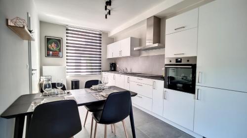 una cocina con armarios blancos y una mesa con sillas. en Appartement cosy et familial avec terrasse, en Theux