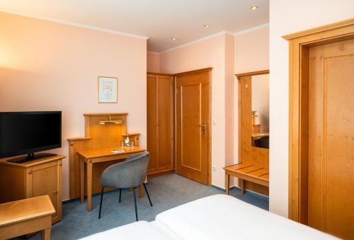 a hotel room with a bed and a desk and a television at Arthotel ANA Fleur in Paderborn