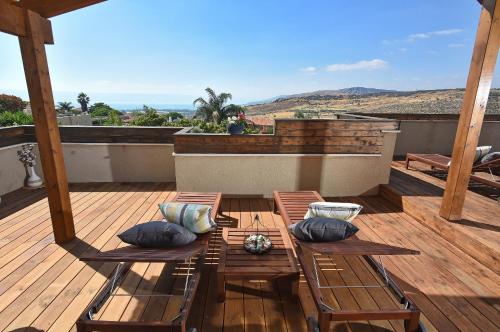 a wooden deck with chairs and a table with pillows at Agama in Livnim