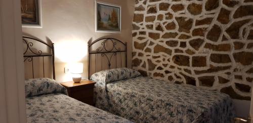 a bedroom with two beds and a stone wall at La cabaña de Seña in Laredo