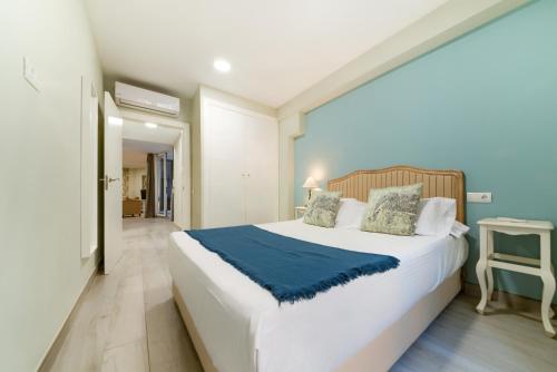 ein Schlafzimmer mit einem großen weißen Bett mit einer blauen Decke in der Unterkunft Holidays2Malaga Suites in Málaga
