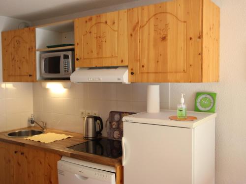 a kitchen with a white refrigerator and wooden cabinets at Studio Chamrousse, 1 pièce, 4 personnes - FR-1-340-243 in Chamrousse