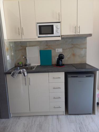 a small kitchen with white cabinets and a microwave at The Palms novasithonia in Vourvourou