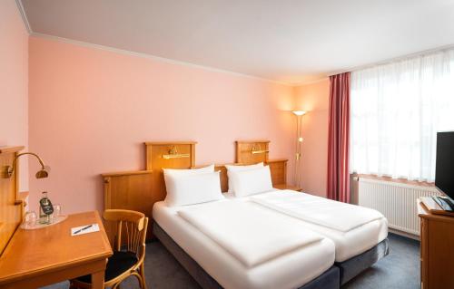 a hotel room with a large bed and a desk at Arthotel ANA Fleur in Paderborn