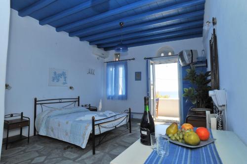 um quarto azul com uma cama e uma mesa com uma tigela de fruta em Drosoulites em Agios Loannis