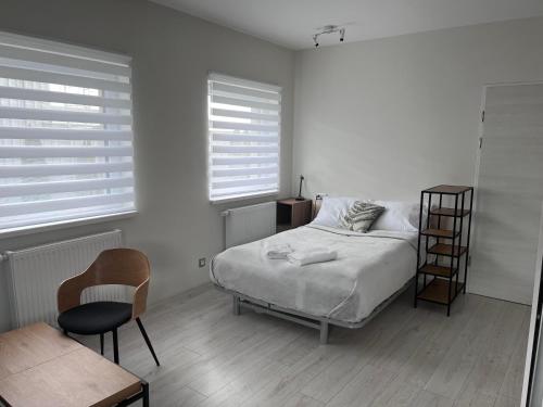 biała sypialnia z łóżkiem i krzesłem w obiekcie Apartament Familijny przy ul. Spokojnej w Kołobrzegu