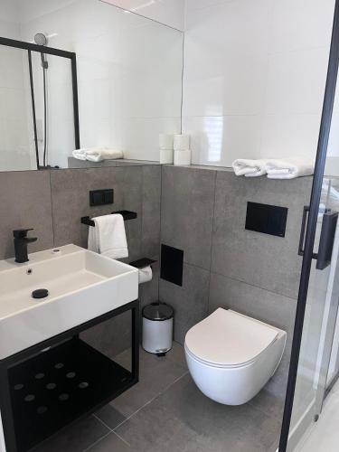 a bathroom with a white toilet and a sink at Apartament Familijny przy ul. Spokojnej in Kołobrzeg