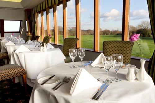 a dining room with white tables and chairs and windows at Dale Hill Hotel in Ticehurst