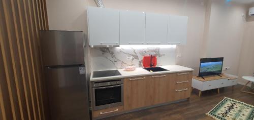 uma cozinha com um frigorífico de aço inoxidável e armários brancos em Eni`s Apartments em Tirana
