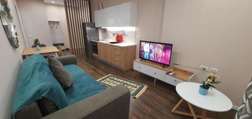 een woonkamer met een blauwe bank en een tv bij Eni`s Apartments in Tirana