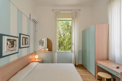 a bedroom with a bed and a desk and a window at Albergo Villa Gradita in Forte dei Marmi